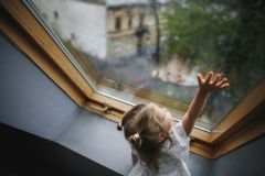 A little girl is looking out of the window